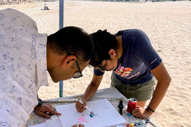 Two guests painting side by side at a stone table