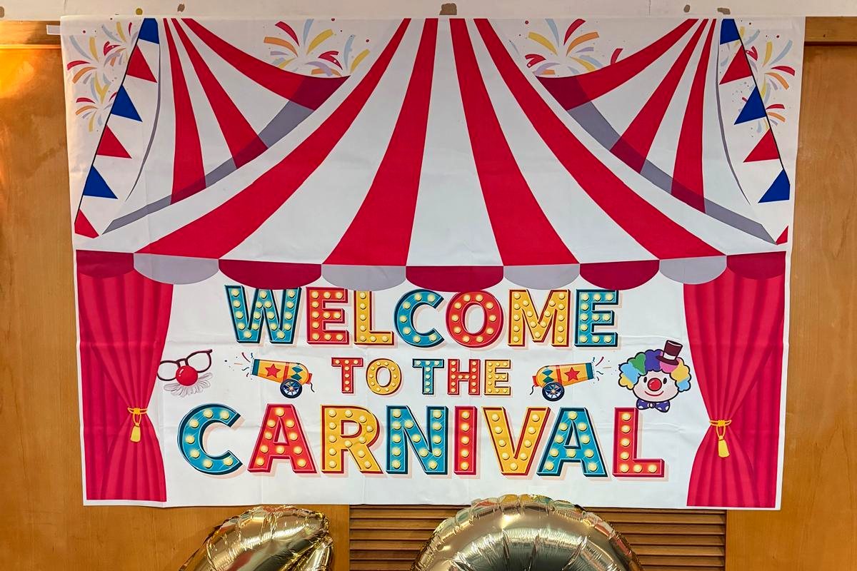 A printed Welcome to the Carnival backdrop with gold forty balloons