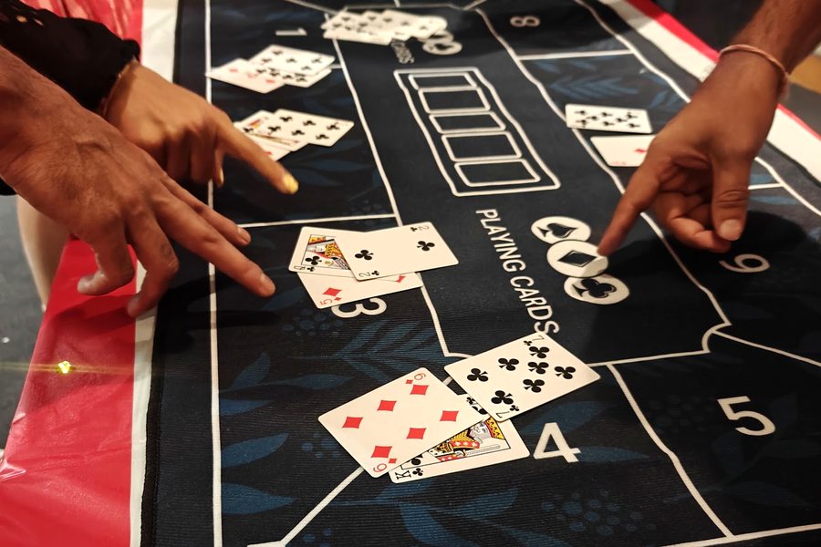Hands dealing cards across a casino table mat